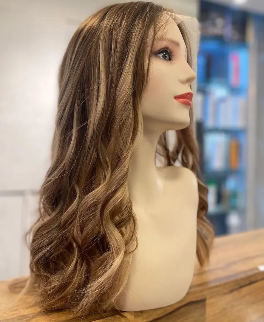 Une perruque longue et ondulée en cheveux naturels sur une tête de présentation au salon Alison WIGS